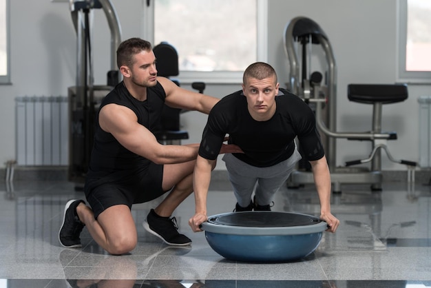 Personal Trainer ajudando o homem nas flexões Bosu