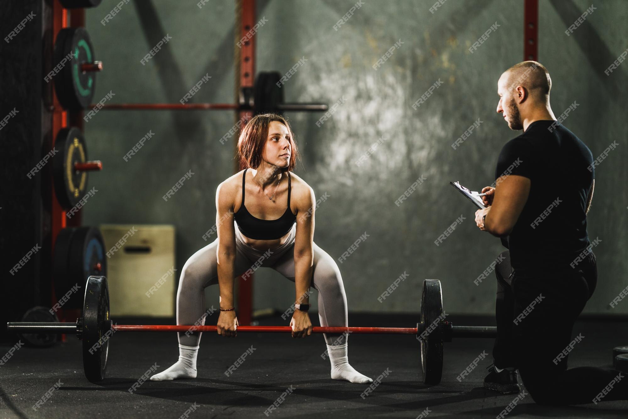 Jovem mulher musculosa em pé com barra na academia pronta para levantamento  terra de sumô