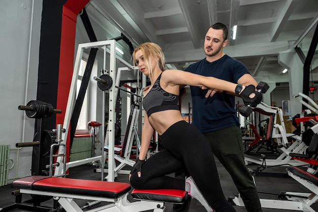 Personal trainer com cliente de mulher magra fazendo bíceps malhando no estilo de vida saudável do ginásio