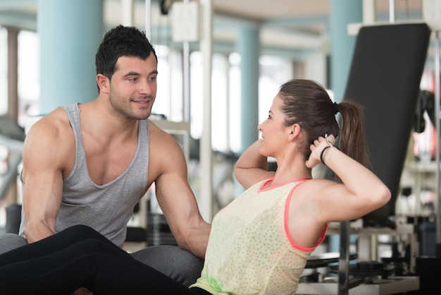 Personal Trainer, der junge Frau zeigt, wie man auf Bosu Abs trainiert, trainiert in einem Gesundheits- und Fitnesskonzept