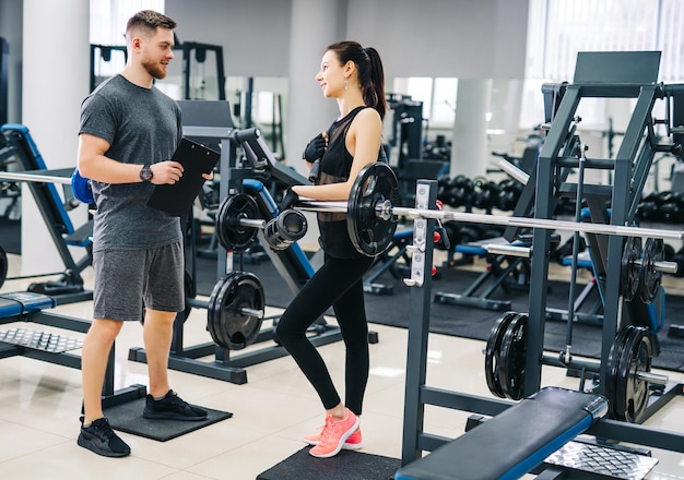 Personal trainer e cliente olhando para seu progresso na academia Atlético homem e mulher vestindo roupas esportivas