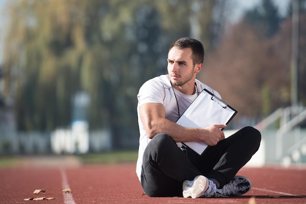 Personal Trainer em roupa de esportes toma notas na prancheta na área do parque da cidade treinamento e exercício para resistência conceito de estilo de vida saudável ao ar livre