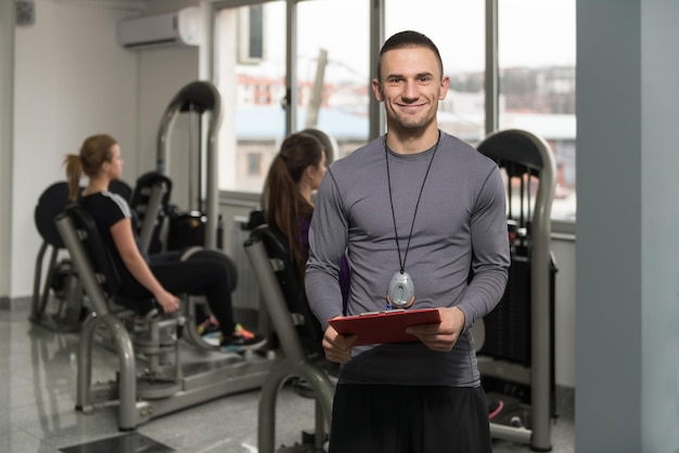 Foto personal trainer faz anotações enquanto mulher exercita as pernas