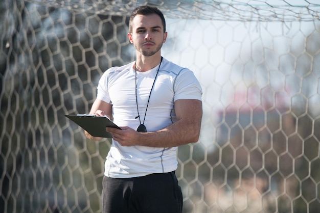 Personal Trainer im Sportoutfit macht sich Notizen auf der Zwischenablage im City Park Area Training und Training für ein gesundes Ausdauerkonzept im Freien