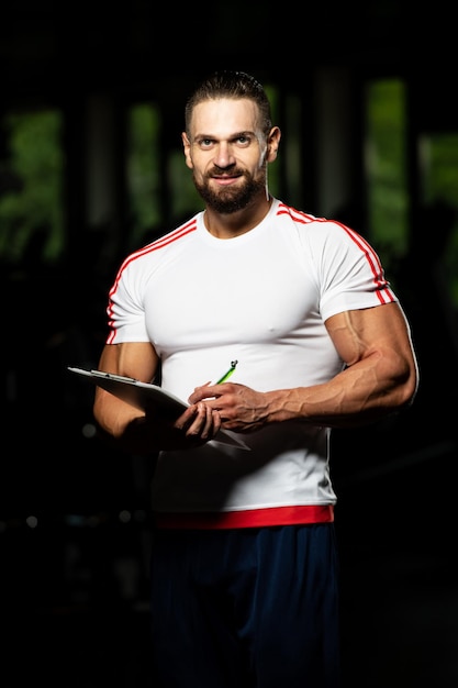 Personal Trainer macht sich Notizen in der Zwischenablage im Fitnesscenter