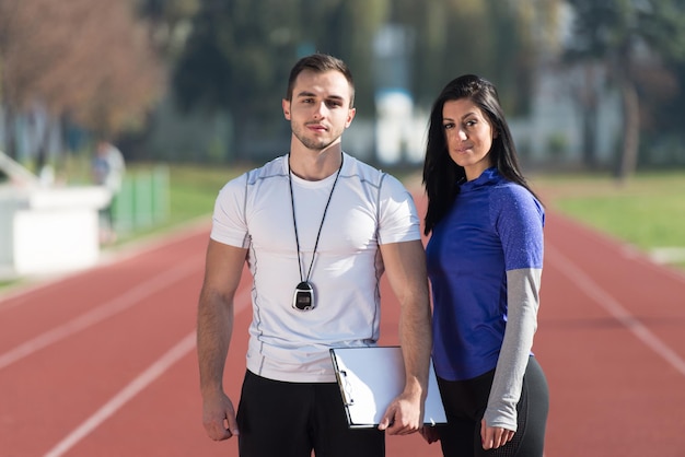 Foto personal trainer toma notas enquanto a jovem se exercita na área do parque da cidade, treinando e exercitando para o conceito de estilo de vida saudável de resistência ao ar livre