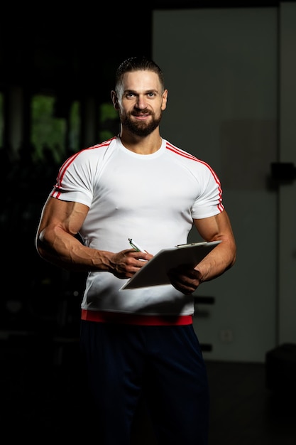 Foto personal trainer toma notas na prancheta no ginásio do centro de fitness