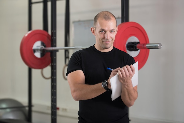 Personal Trainer toma notas na prancheta no ginásio do centro de fitness