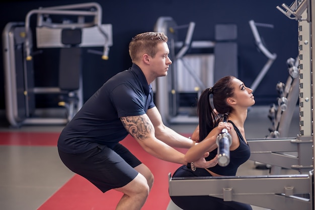 Personal Trainer und fit Frau arbeiten mit Langhantel