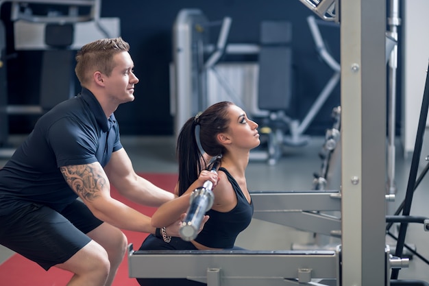 Personal Trainer und fit Frau arbeiten mit Langhantel