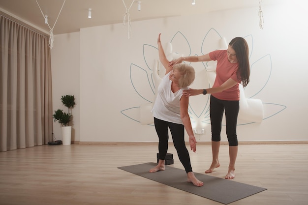 Personal Trainerin, die mit Seniorin im Sportstudio arbeitet, Kopierraum