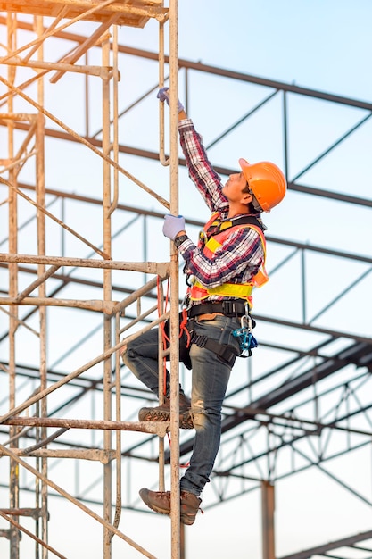 Personal vestido con uniforme de acuerdo con las normas de seguridad Está subiendo al andamio para ver el trabajo en el sitio de construcción