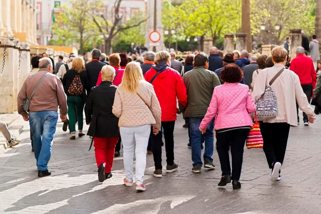 Foto personas anónimas caminando siguiendo al guía turístico en la calle de la ciudad de sevilla, españa