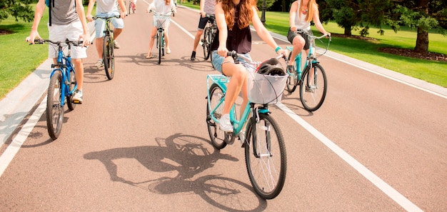 Foto personas en bicicleta en el parque de la ciudad en la carretera asfaltada. estilo de vida saludable y cuidado de la salud. corte la vista de cinco personas divirtiéndose juntas en la carretera. hermoso día soleado afuera