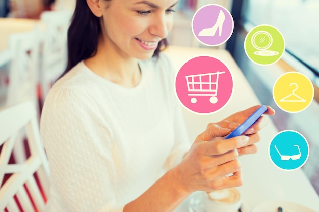 personas, compras en línea, tecnología y concepto de estilo de vida - mujer joven sonriente con iconos de teléfono inteligente e Internet en el café