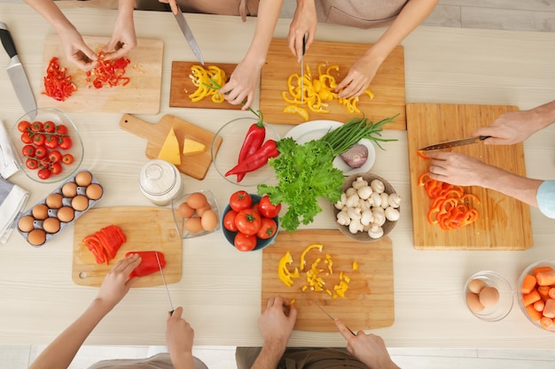 Personas cortando verduras en clases de cocina.