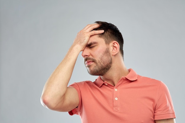 personas, crisis, emociones y estrés concepto - hombre infeliz que sufre de dolor de cabeza sobre fondo gris