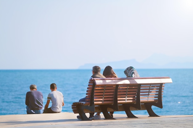 Personas de diversas religiones descansan y se sientan una al lado de la otra en un banco contra el fondo del mar