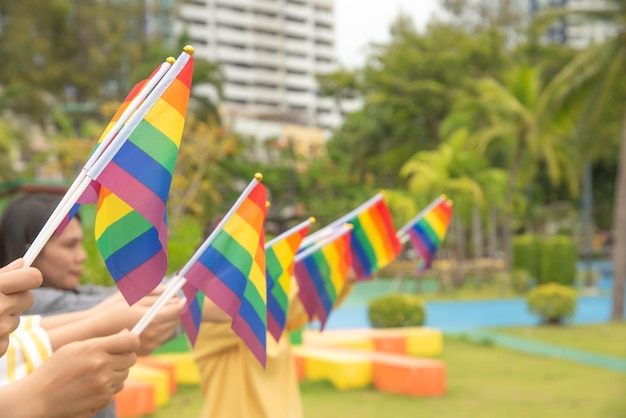 Foto personas de la diversidad manos levantando coloridas banderas del arco iris lgbtq juntas un símbolo para la comunidad lgbt