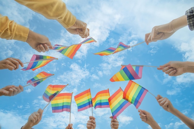 Personas de la diversidad manos levantando coloridas banderas del arco iris lgbtq juntas un símbolo para la comunidad LGBT