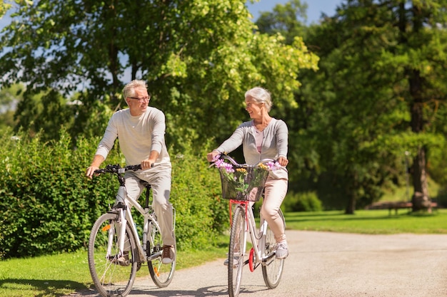 Foto personas de edad avanzada activas y concepto de estilo de vida pareja de ancianos felices montando bicicletas en el parque de verano