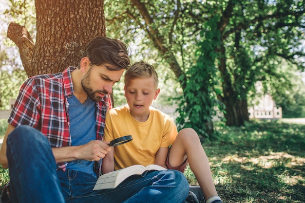 las personas están sentadas juntas debajo del árbol y mirando el libro