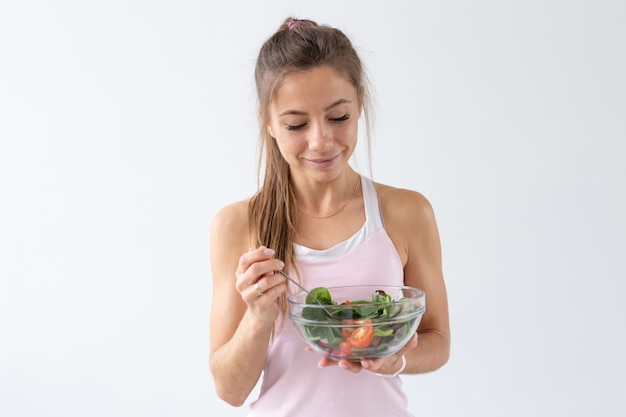 Foto personas, estilo de vida saludable y concepto de fitness - hermosa mujer joven después de hacer ejercicio comiendo una ensalada saludable.