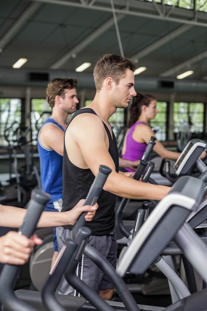 Personas en forma en bicicleta elíptica en el gimnasio