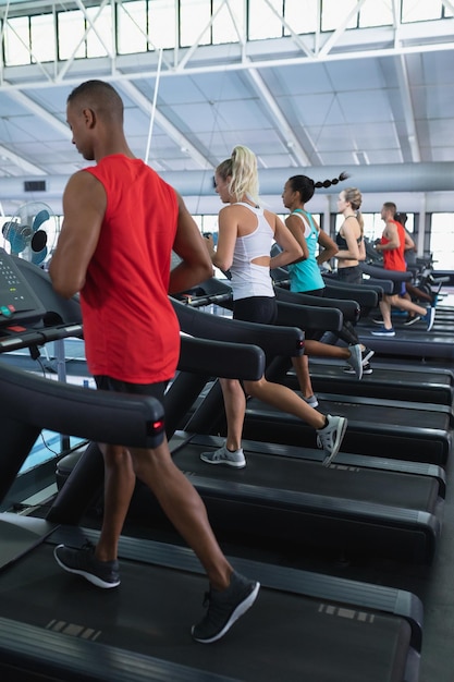Foto personas en forma haciendo ejercicio en una cinta de correr en un gimnasio