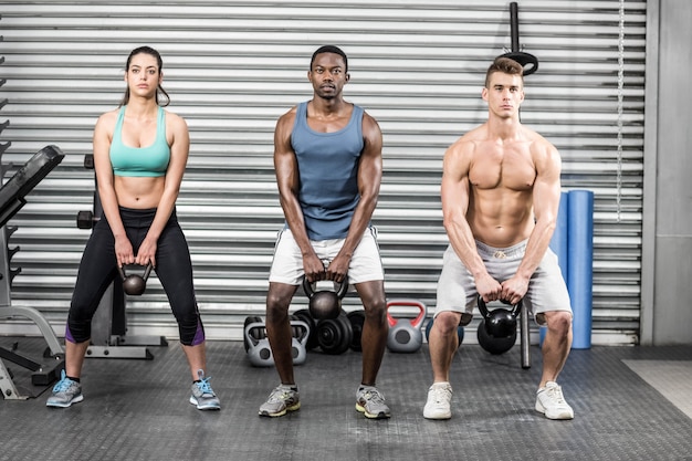 Foto personas en forma levantando pesas en el gimnasio de crossfit