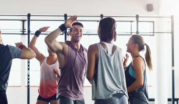 Las personas fuertes inspiran a otras personas a ser fuertes Foto de un grupo de jóvenes que se motivan unos a otros chocando los cinco en un gimnasio