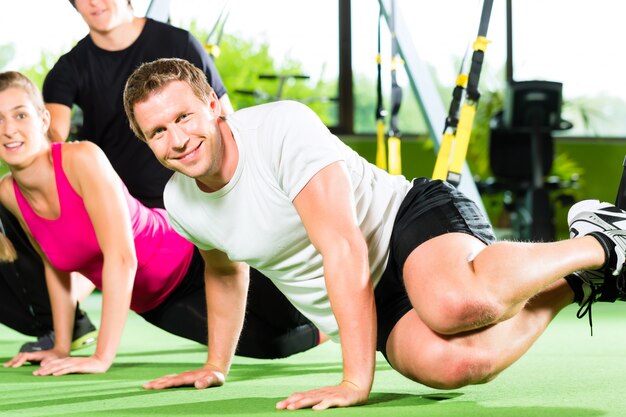 Personas en el gimnasio deportivo en entrenador de suspensión