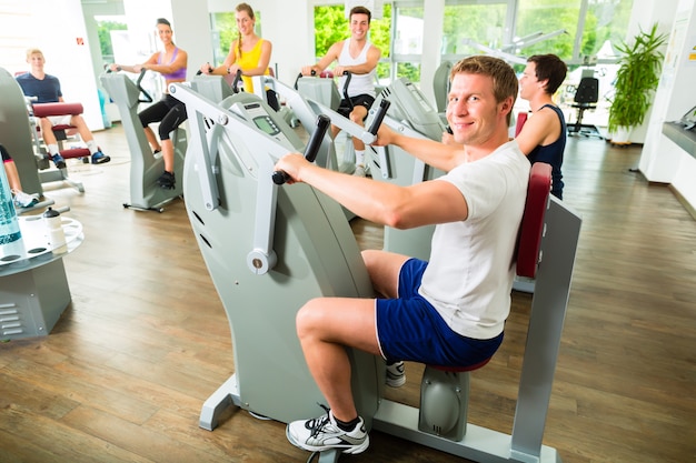 Personas en gimnasio deportivo en máquinas.