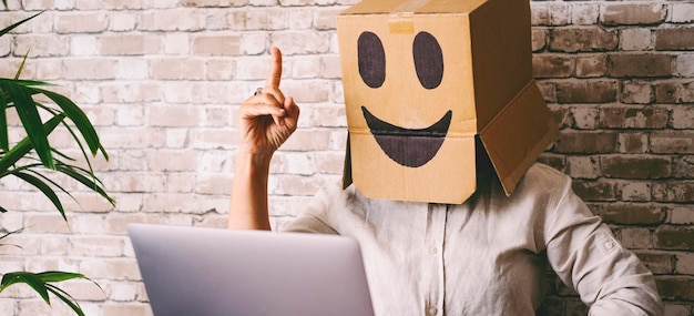 Personas con identidad ho que trabajan en computadoras portátiles y conexión a Internet que tienen una idea Mujer con una caja de cartón en la cabeza con una sonrisa Feliz trabajo inteligente en línea Oportunidades de trabajo web Privacidad moderna