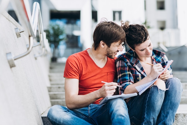 Las personas jóvenes inteligentes están usando gadgets y sonriendo mientras estudian