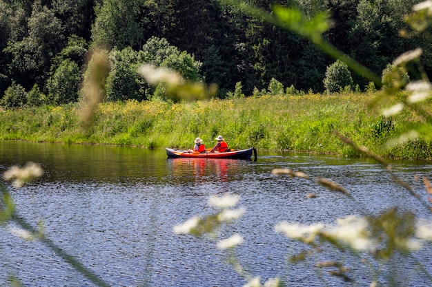 Personas en un kayak en el río contra el fondo del bosque. Deportes activos de verano. Precioso paisaje.