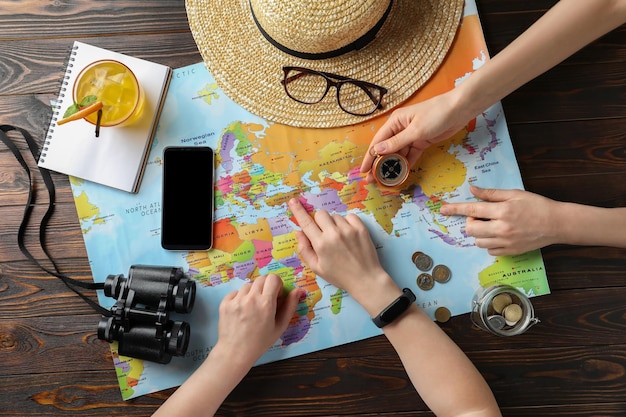 Personas con mapa del mundo y accesorios en la vista superior de la mesa Viajar durante las vacaciones de verano