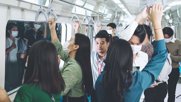 Personas con máscaras faciales en un tren subterráneo público abarrotado