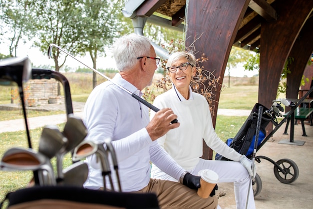 Personas mayores jubiladas hablando y riendo antes del entrenamiento de golf.