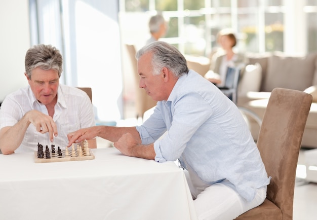 Personas mayores jugando al ajedrez en la sala de estar