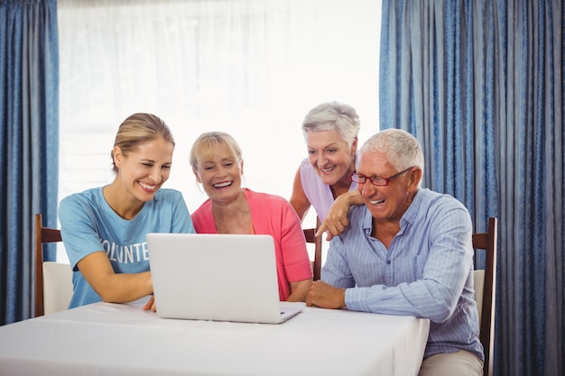 Personas mayores y mujer usando laptop