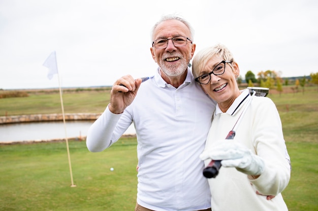 Personas mayores con palos de golf jugando su deporte favorito y disfrutando del tiempo recreativo