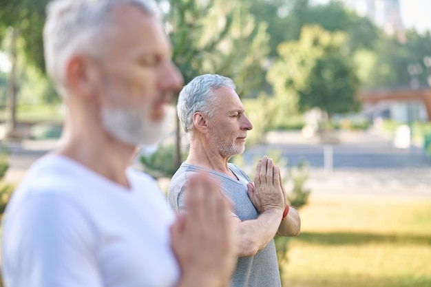 Personas de mediana edad que tienen clase de yoga en el parque