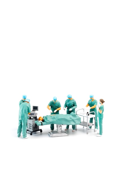 Personas en miniatura Doctor realizando cirugía al paciente sobre fondo blanco.