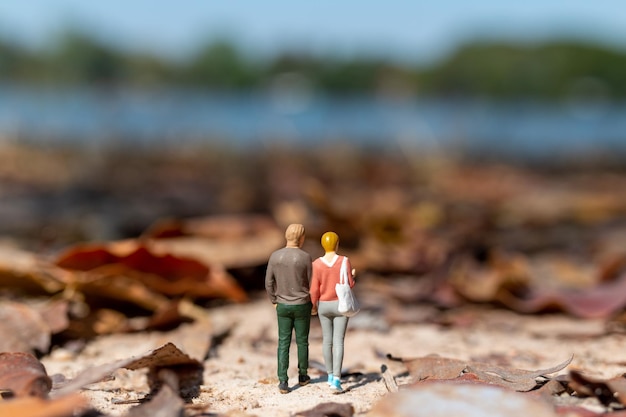 Personas en miniatura Jóvenes amantes cogidos de la mano mientras pasean por un parque en otoño