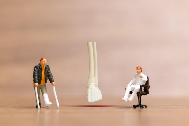 Personas en miniatura Los pacientes con lesiones en las piernas son discutidos por un médico ortopédico