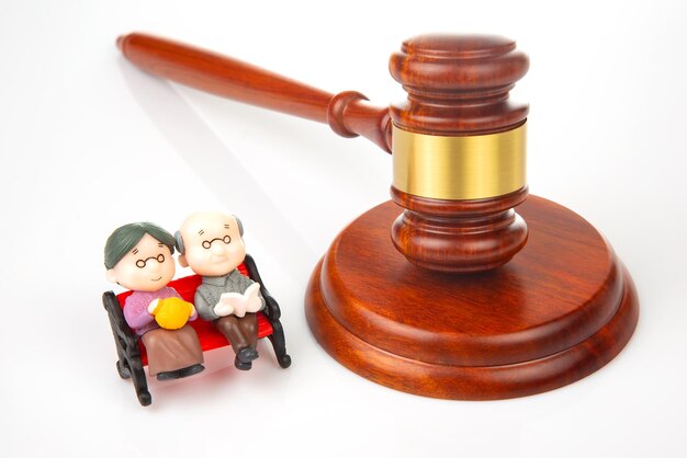Personas en miniatura Pareja de ancianos cerca del mazo de la ley y la justicia Leyes para garantizar la vida de los jubilados