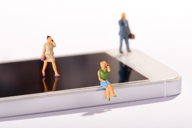 Personas en miniatura que usan teléfonos móviles