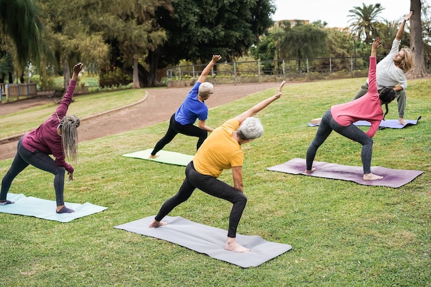 Personas multigeneracionales haciendo clases de yoga en el parque de la ciudad - Centrarse en el centro de la cabeza de la mujer