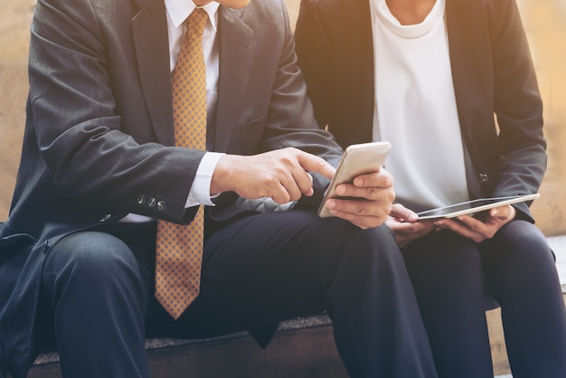 Las personas de negocios usan el teléfono móvil en la ciudad.